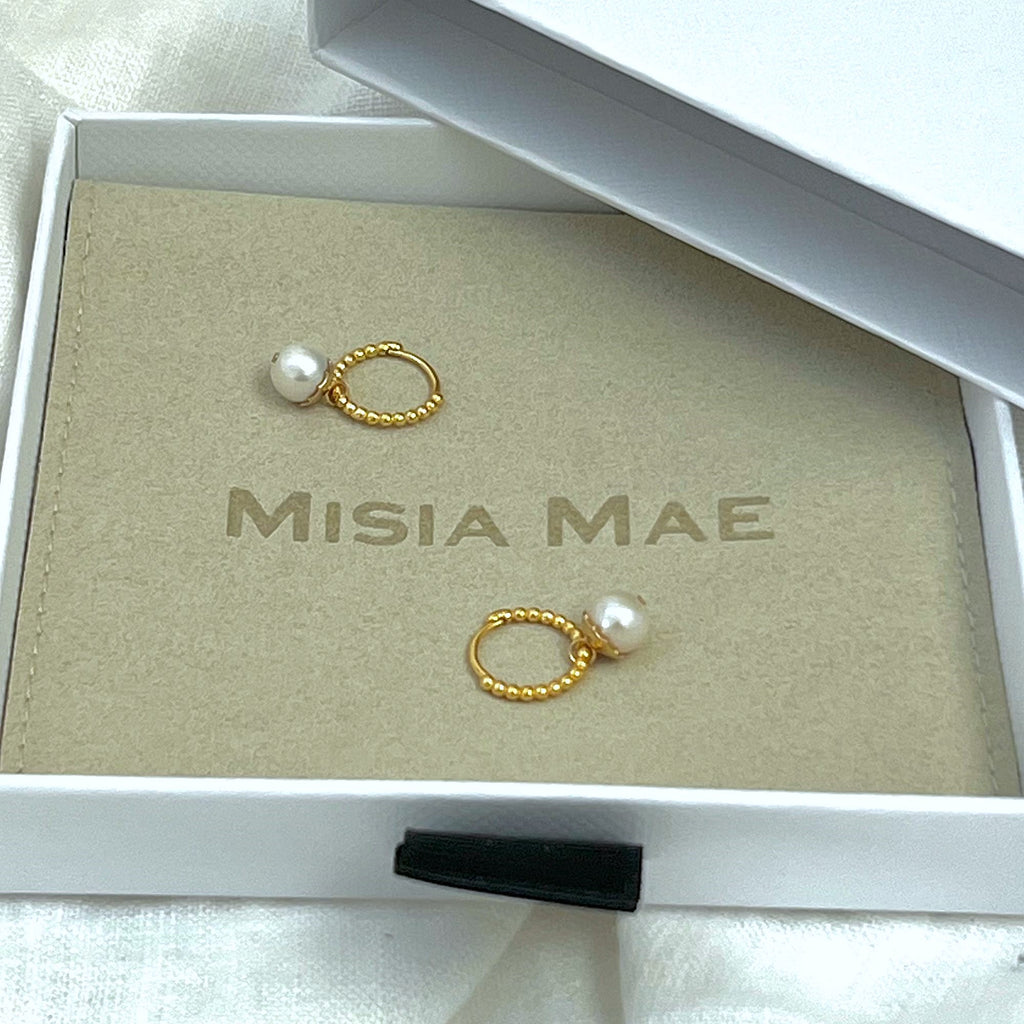 Gold beaded huggie hoop earrings with pearls on a Misia Mae flat pouch in a jewellery box and white linen background