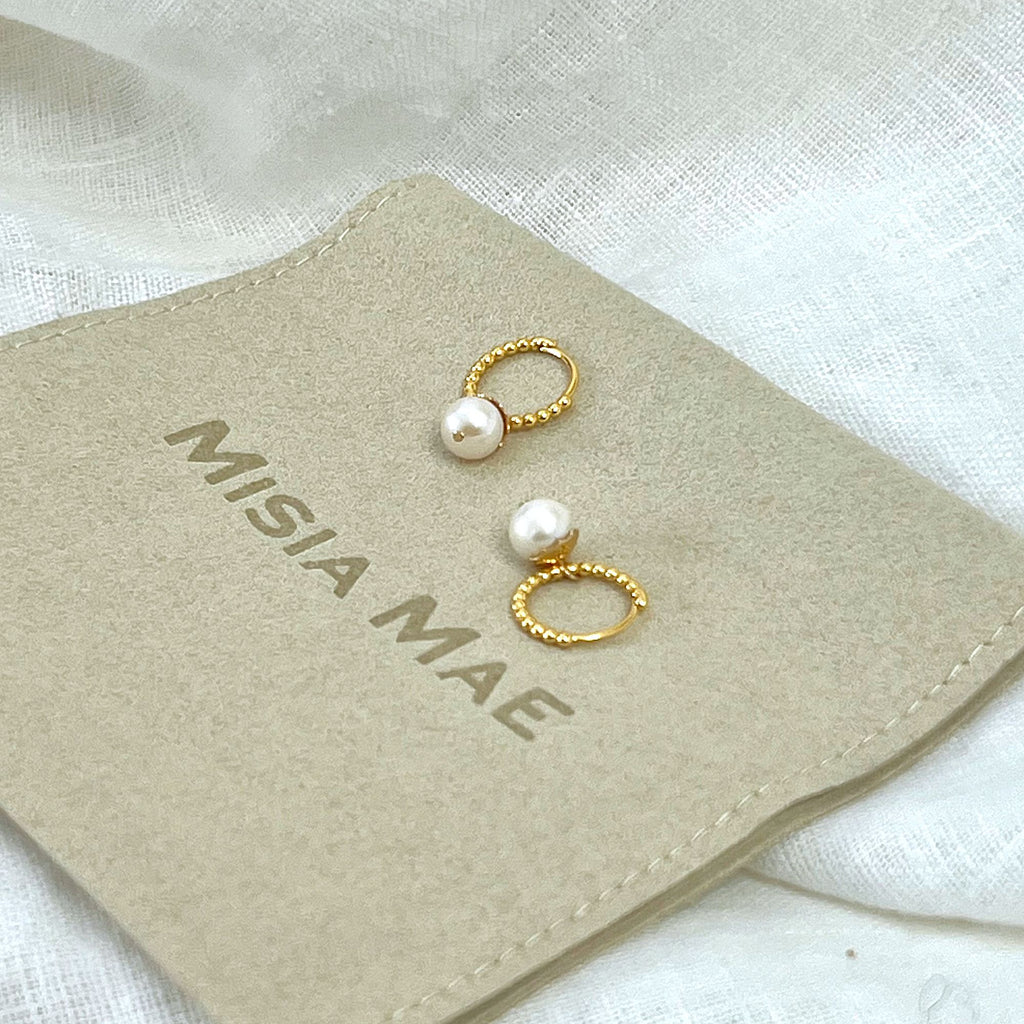 Beaded huggie hoop earrings with pearls on a Misia Mae flat pouch and white linen background 