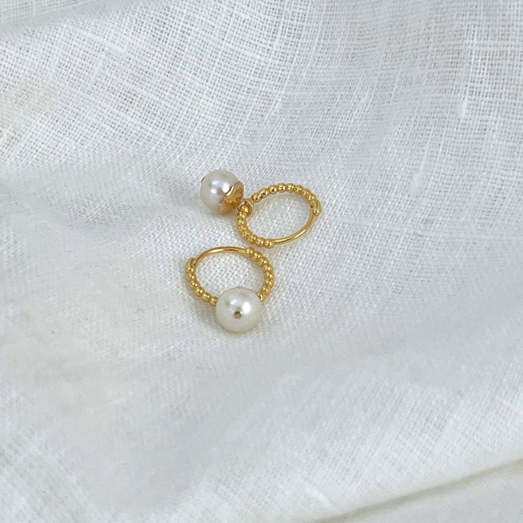 Beaded huggie hoop earrings with pearls on  white linen background