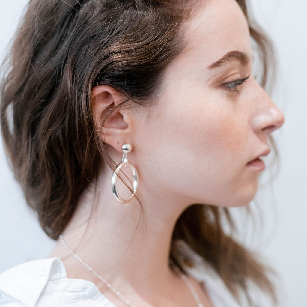 A dark blonde woman wearing a large silver hoop earrings by Misia Mae