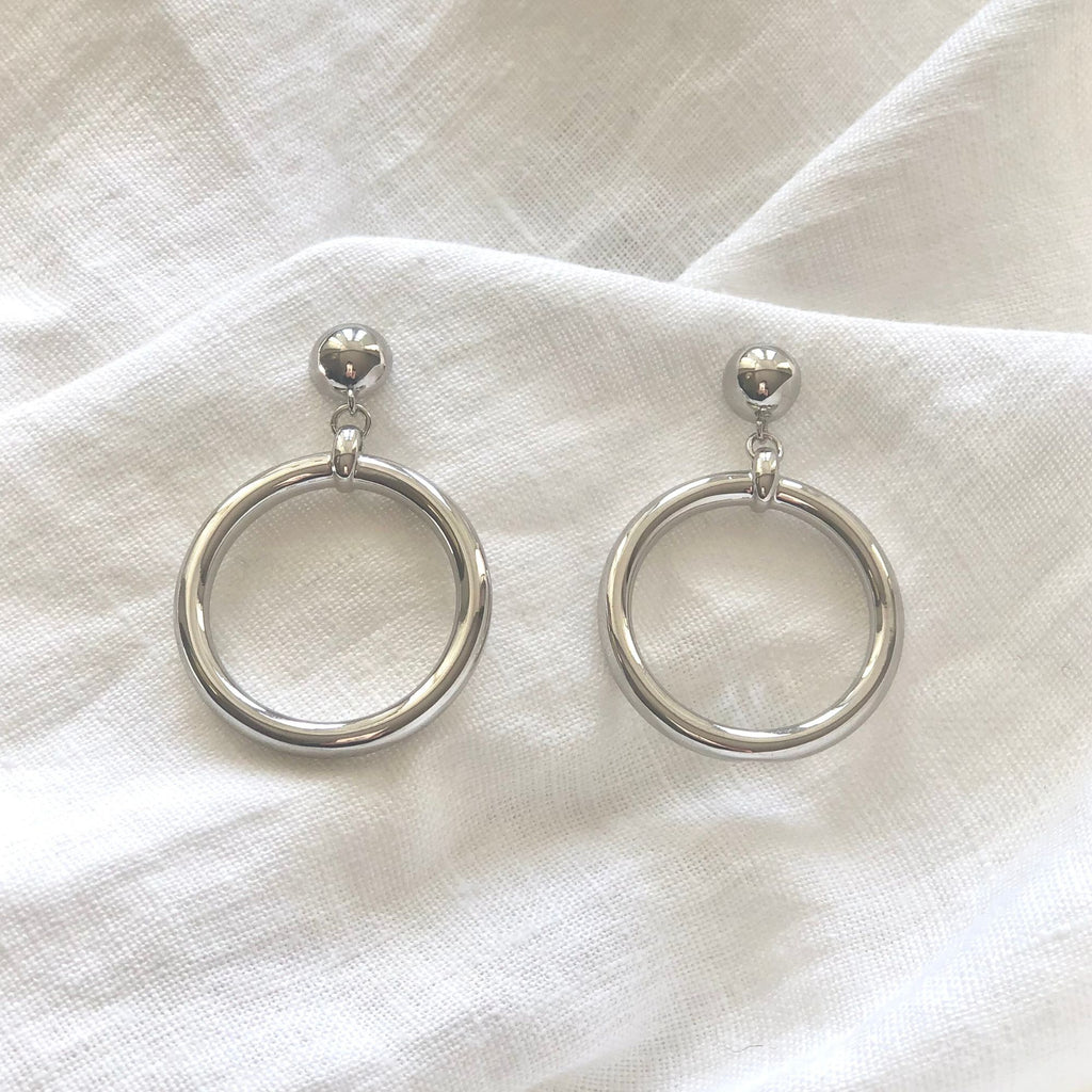 large silver hoop earrings by Misia Mae on a white linen fabric