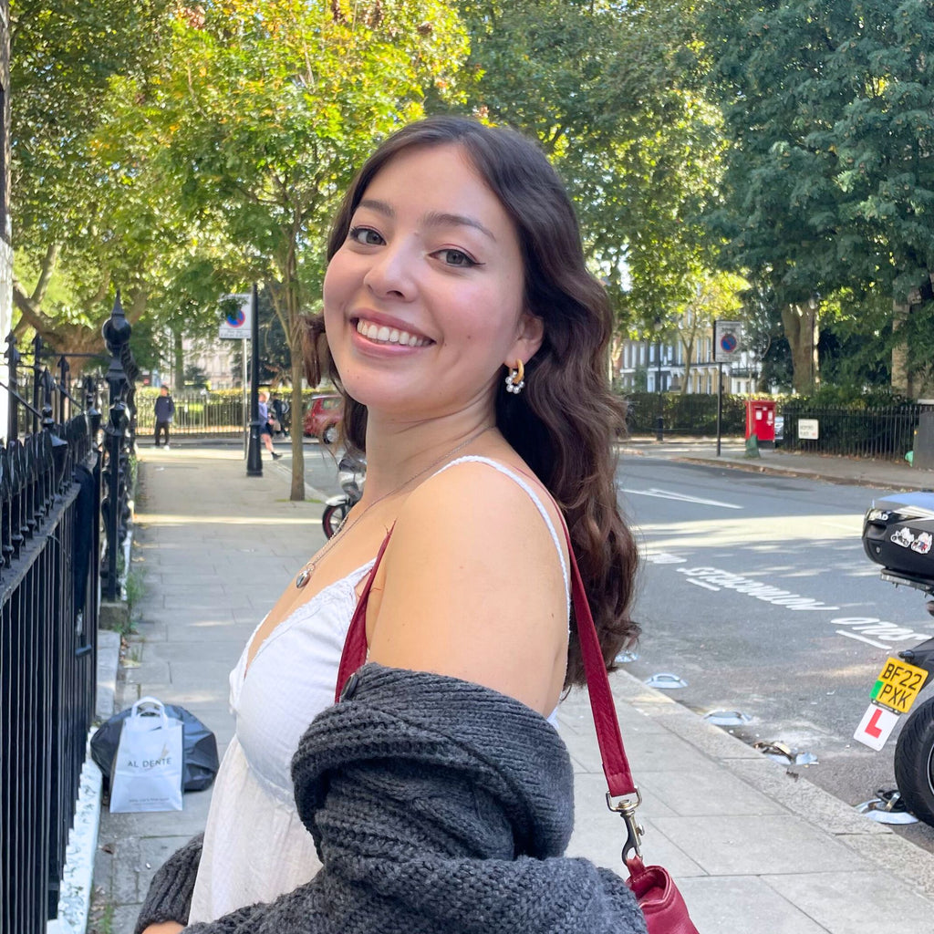 A brunette young woman wearing textured gold hoop earrings with pearl charms by Misia Mae