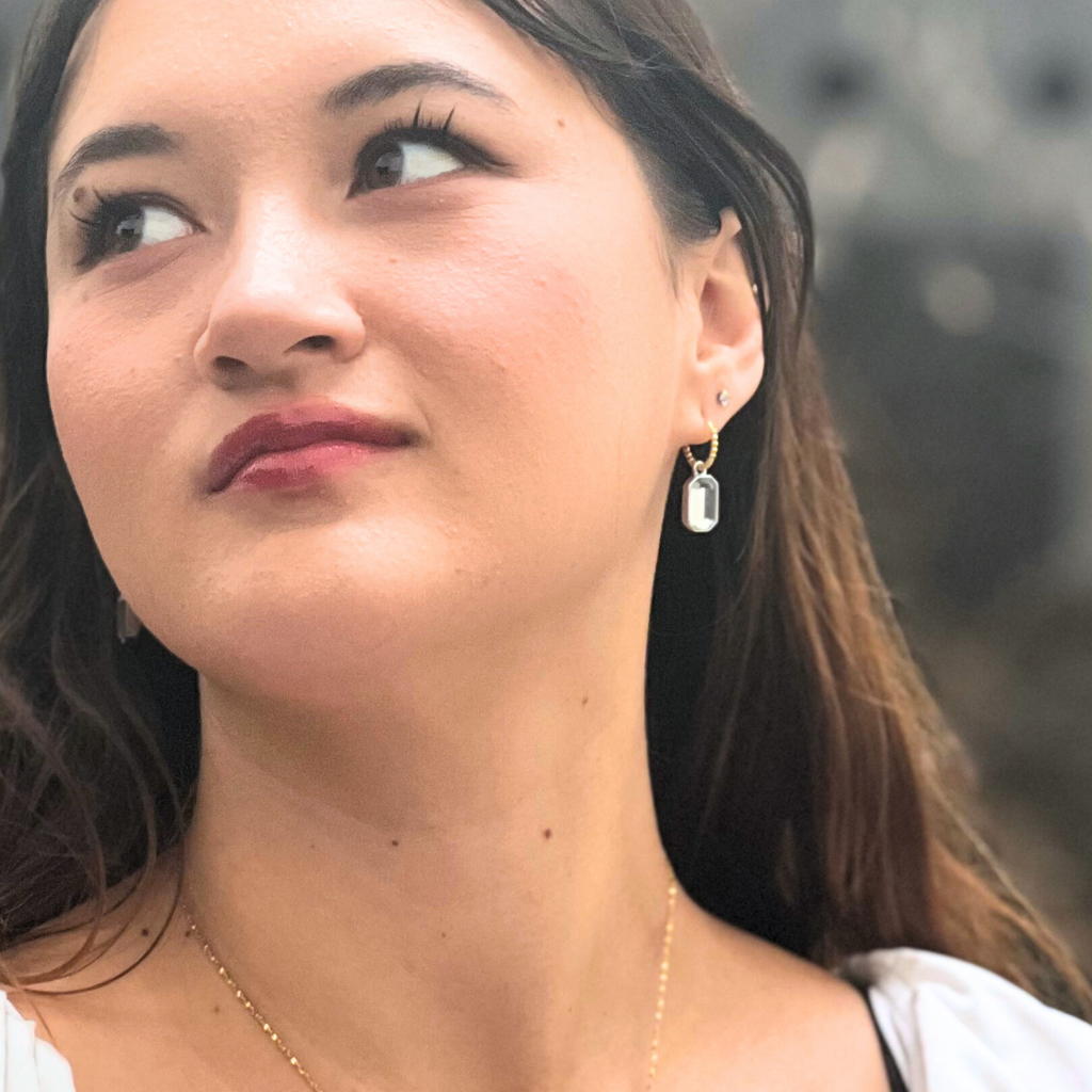 A brunette woman wearing mixed metal earrings 