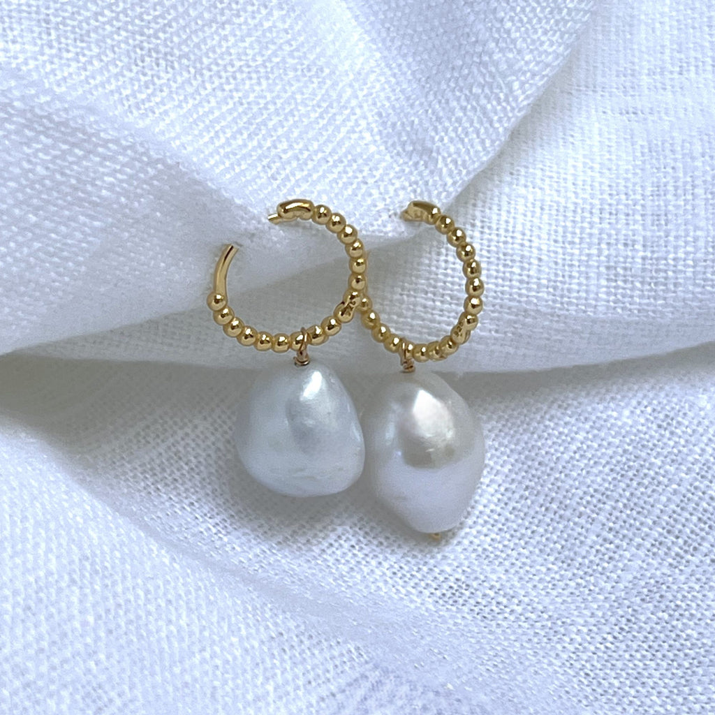 baroque pearl beaded gold huggies earrings on a white linen background. Earrings by Misia Mae