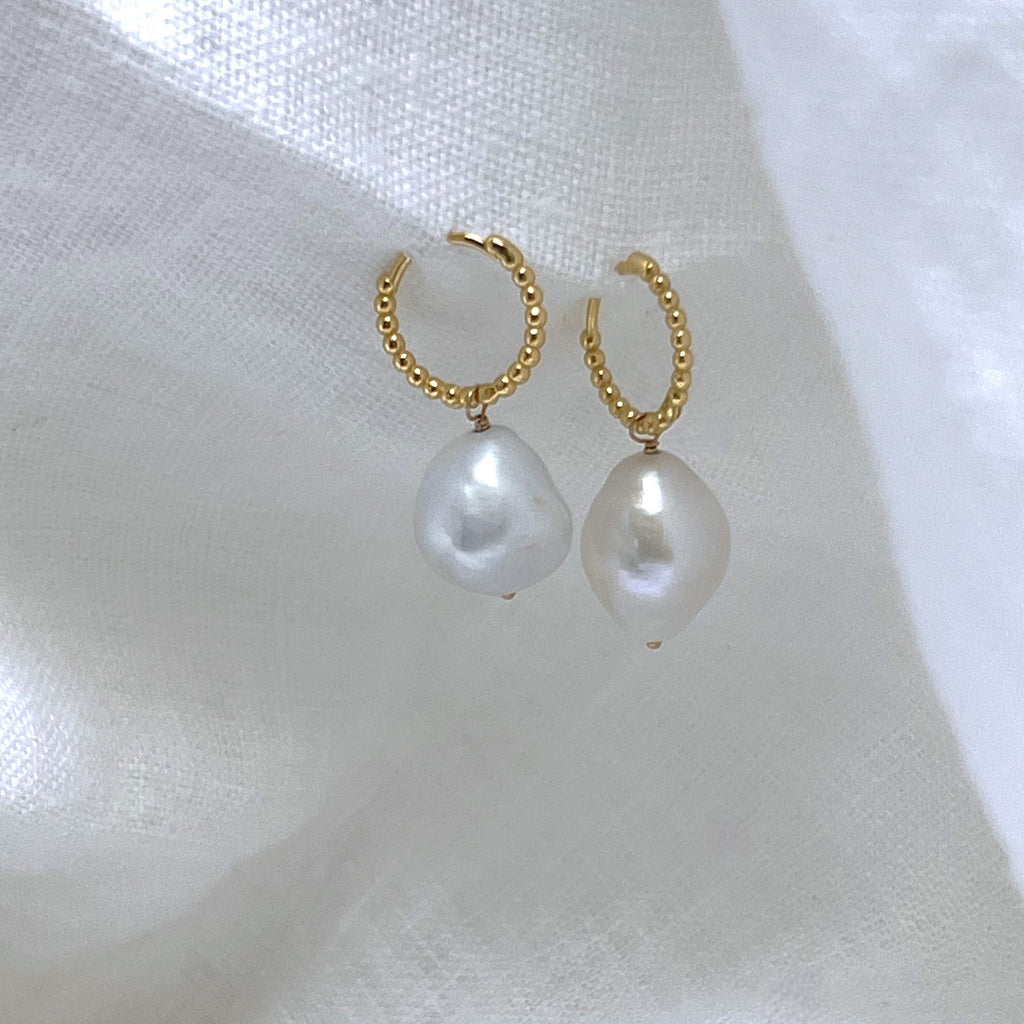 baroque pearl beaded gold huggies earrings on a white linen background. Earrings by Misia Mae