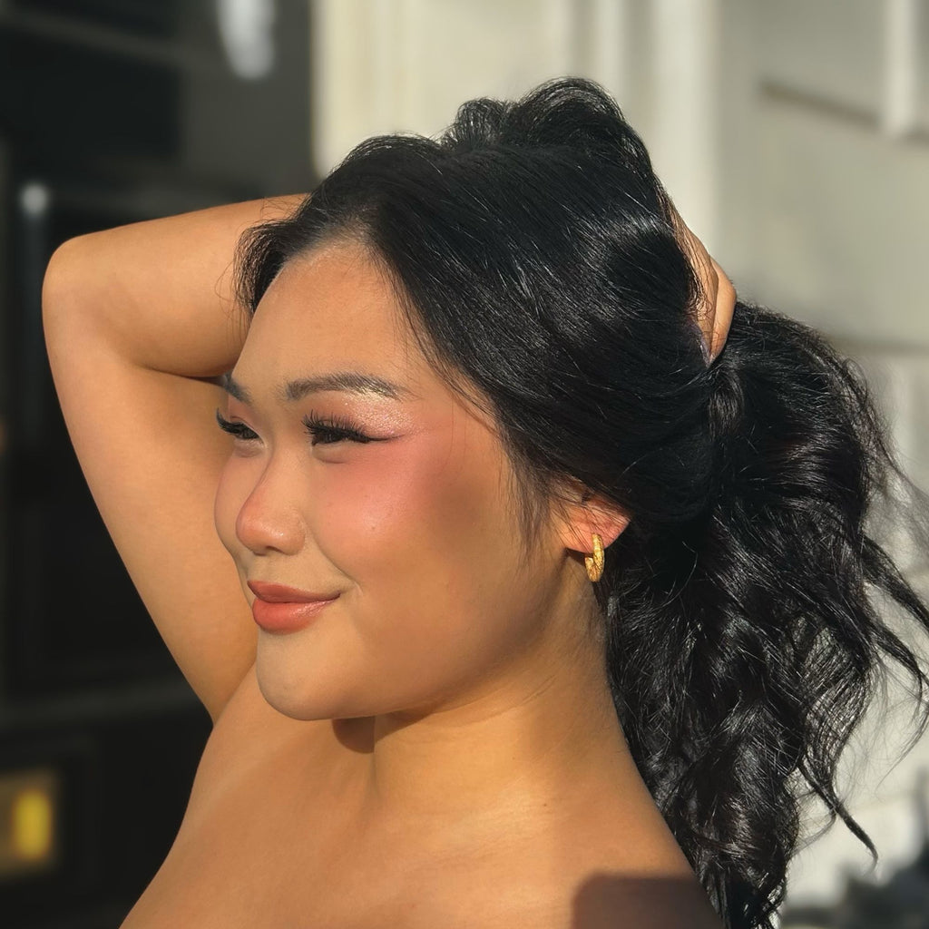 A brunette woman wearing chunky earrings gold