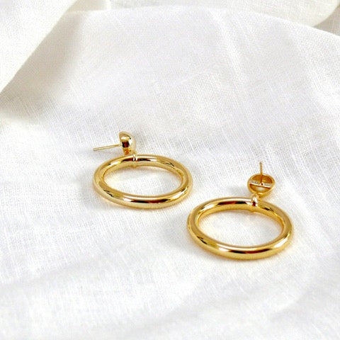 chunky gold hoop earrings on a white linen cloth. The earrings are by Misia Mae
