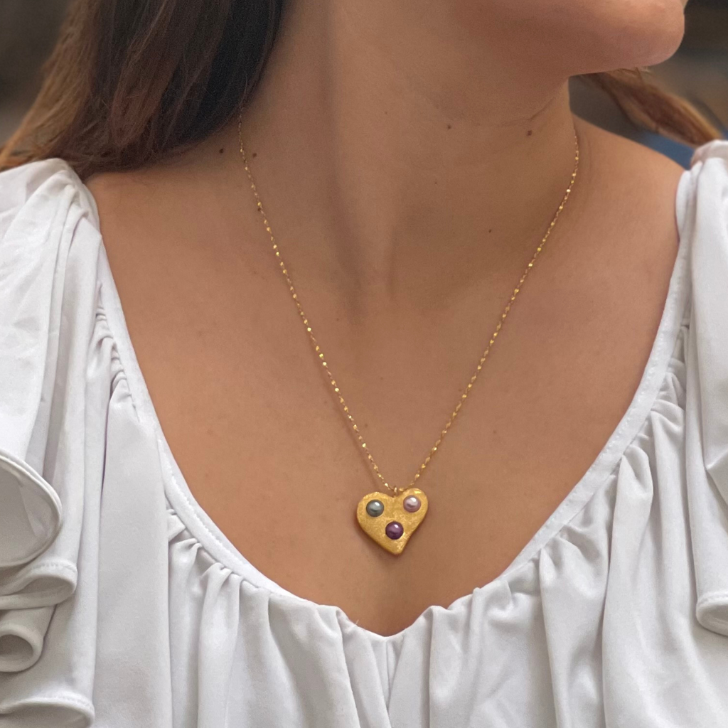 a brunette woman in a white shirt wearing gold heart necklace by Misia Mae