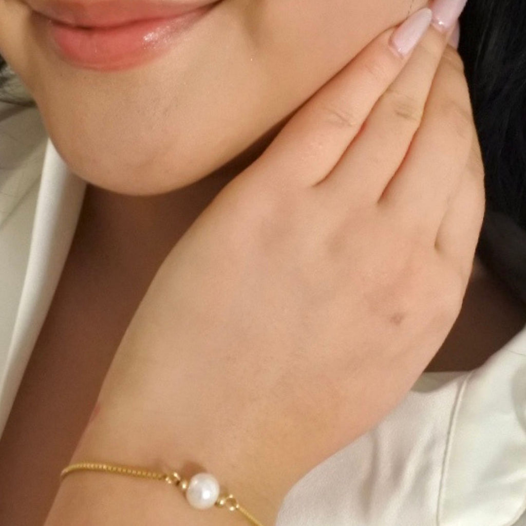 A woman wearing a gold pull through bracelet with pearl