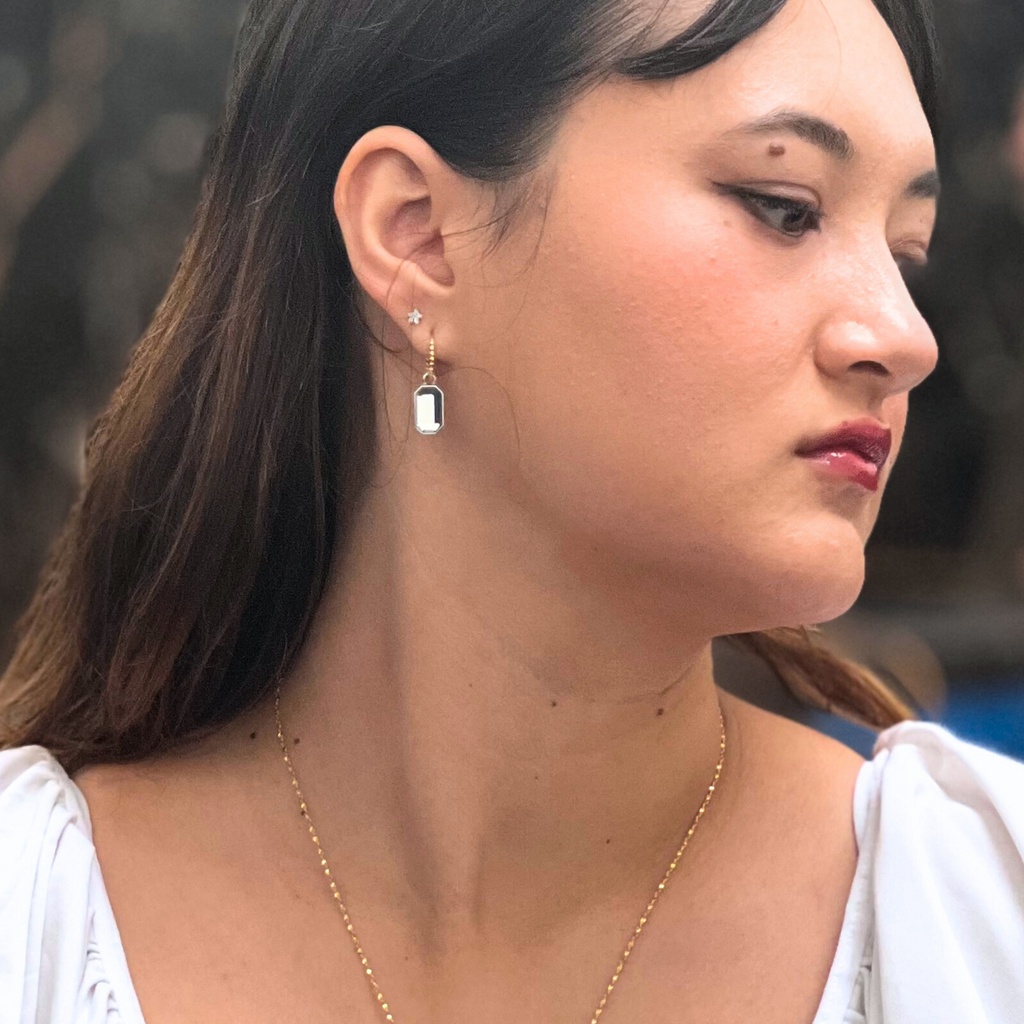 A brunette woman wearing mixed metal earrings 