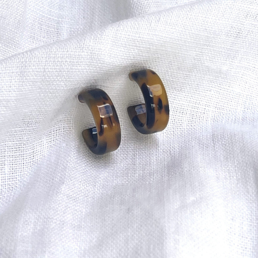 Tortoiseshell earrings brunette on a white linen fabric. Earrings by Misia Mae