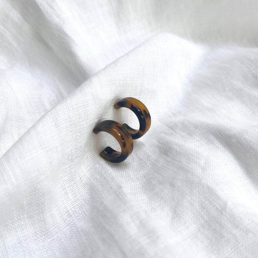 Tortoiseshell earrings brunette on a white linen fabric. Earrings by Misia Mae