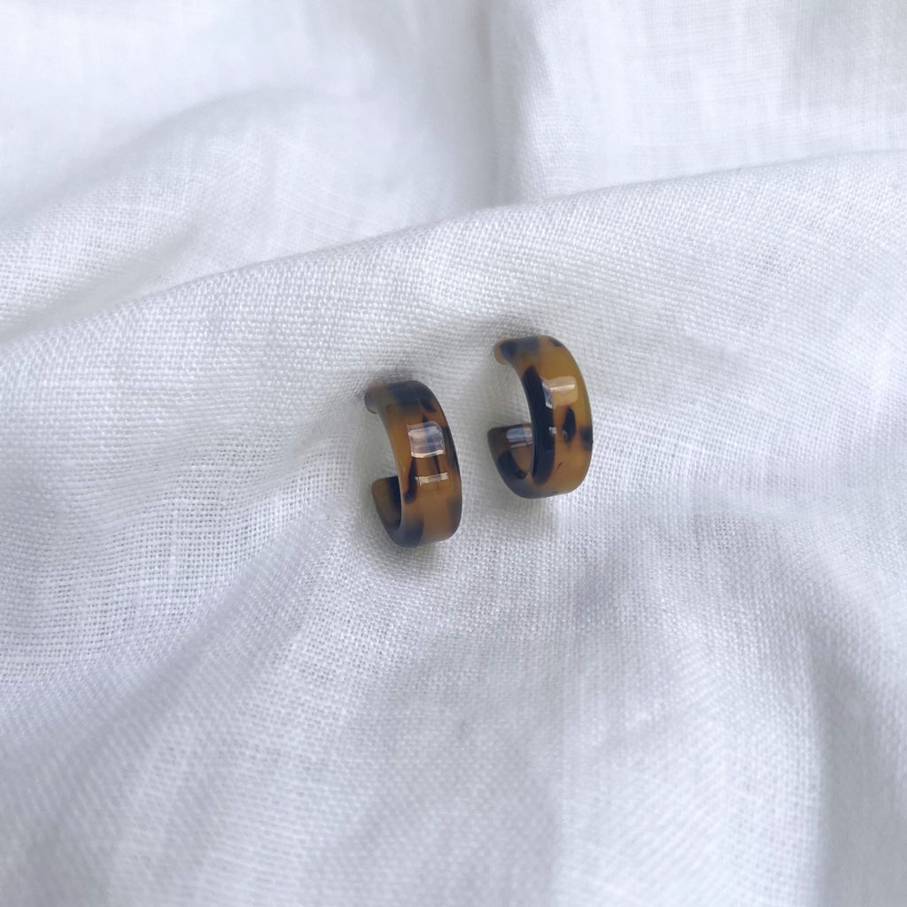 Tortoiseshell earrings brunette on a white linen fabric. Earrings by Misia Mae