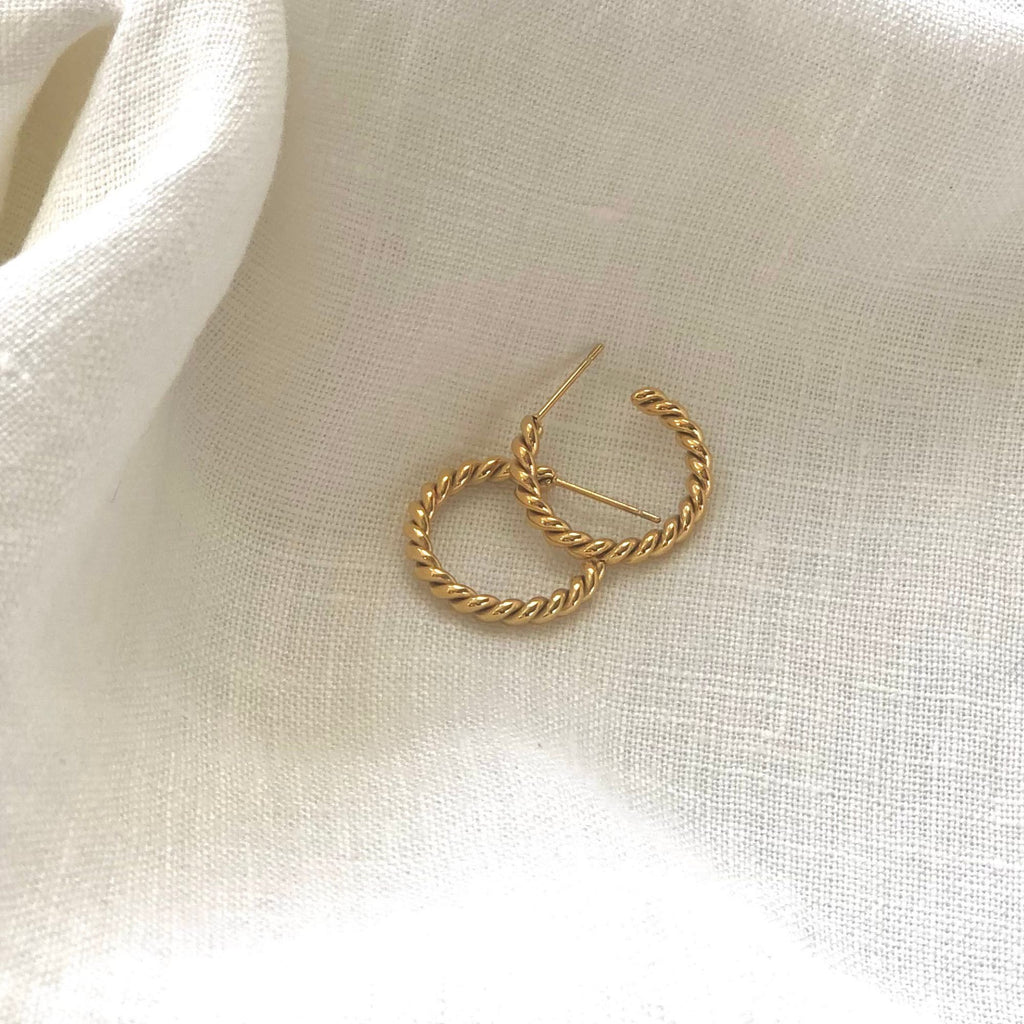 twisted gold earrings from the Iris collection by Misia Mae on a white linen cloth