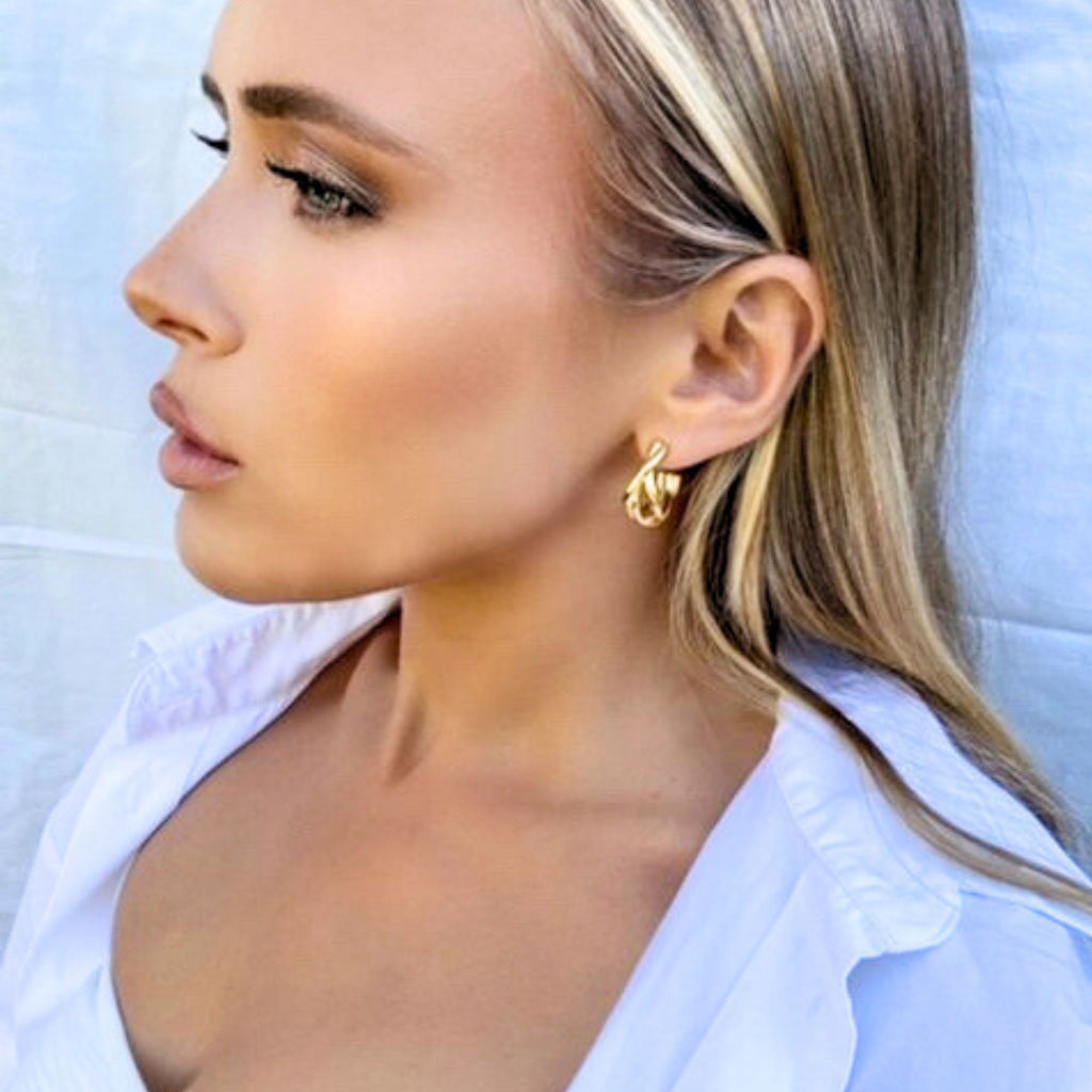 A blonde woman in a white shirt wearing twisted hoop earrings by Misia Mae